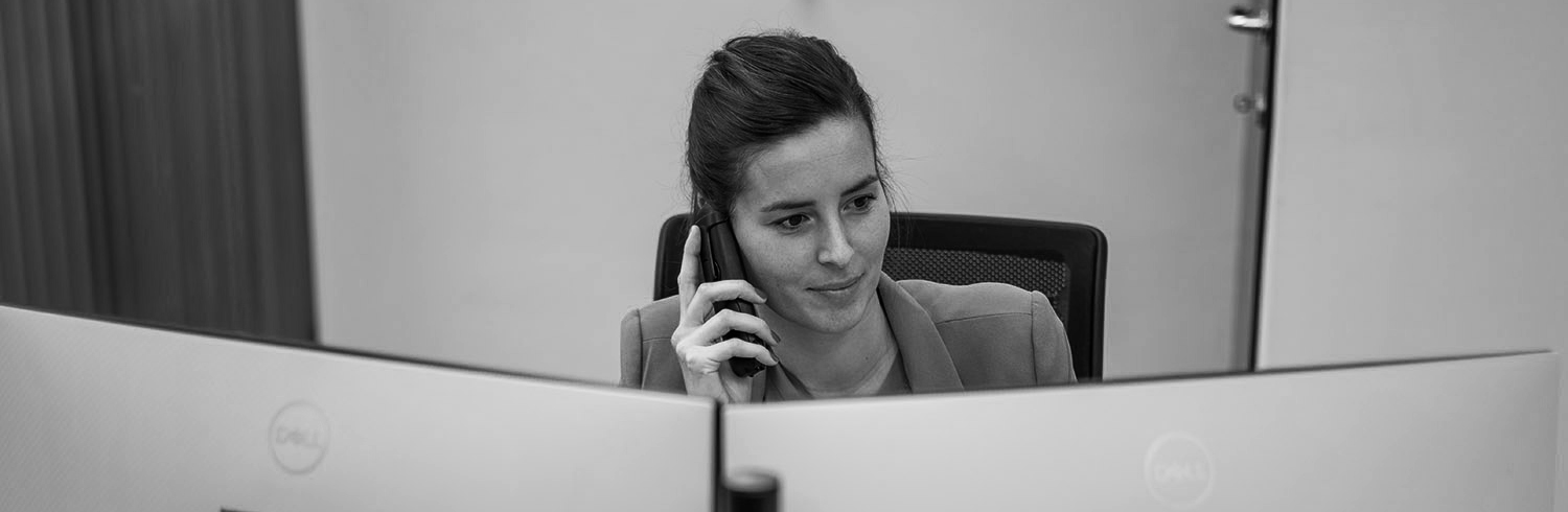 Medewerker van CoatR aan de telefoon achter twee beeldschermen