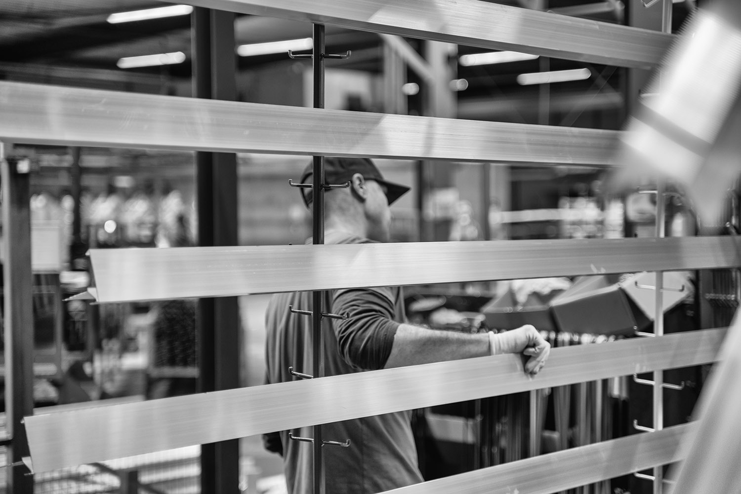 Medewerker in de poedercoatfabriek tussen opgehangen aluminium profielen