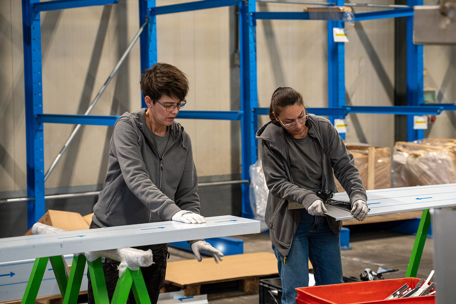 Twee medewerkers met handschoenen bekijken aluminium profielen op schragen