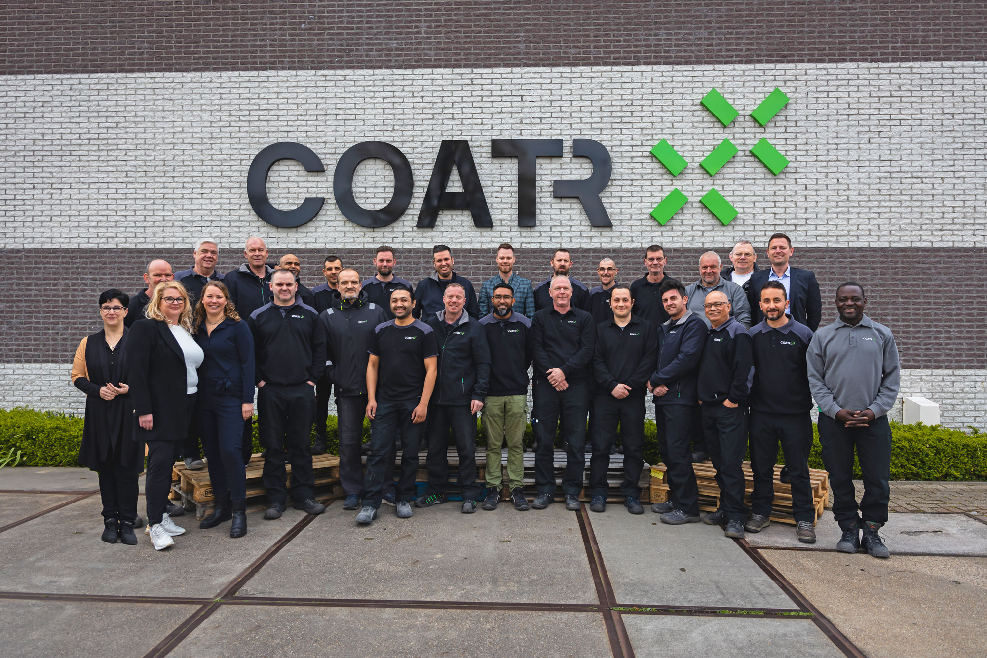 Het team van CoatR voor het bedrijfspand met het CoatR-logo